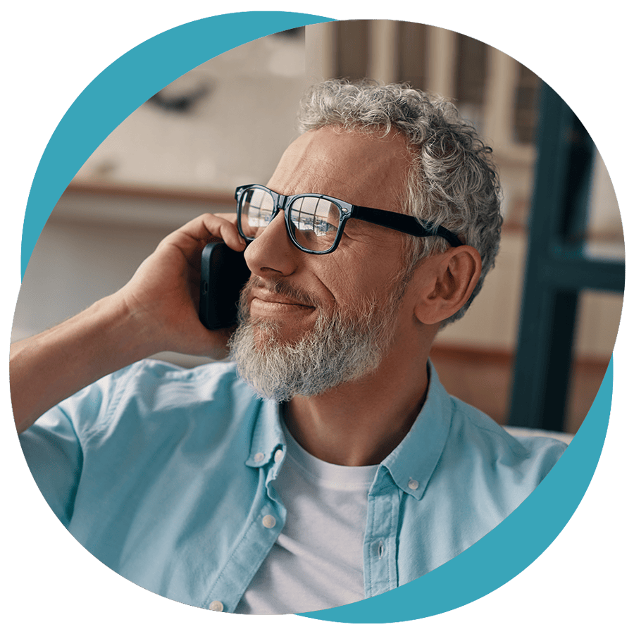 A man looking out the window while chatting on the phone